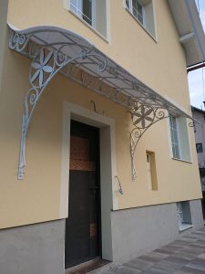 Kovan nadstrešek nad vrati v beli barvi in zlati patini