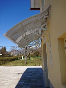 Kovan nadstrešek nad vrati v beli barvi in zlati patini